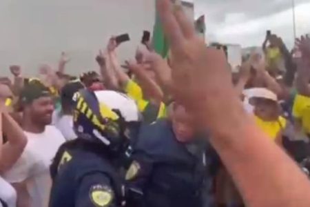 foto colorida de manifestantes com um policial rodoviário federal ao centro