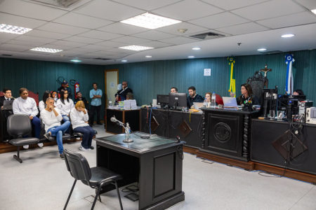 A ex-deputada e cantora gospel Flordelis, acusada de matar o marido, durante julgamento frente à mesa julgadora. Ela usa cabelo curto e loiro, moletom e aparece sentada com a mão na cabeça e olhos fechados - Metrópoles