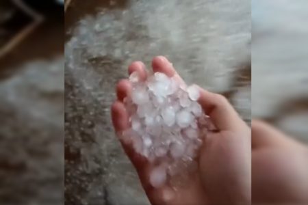 Foto de uma mão segurando pedras de granizo