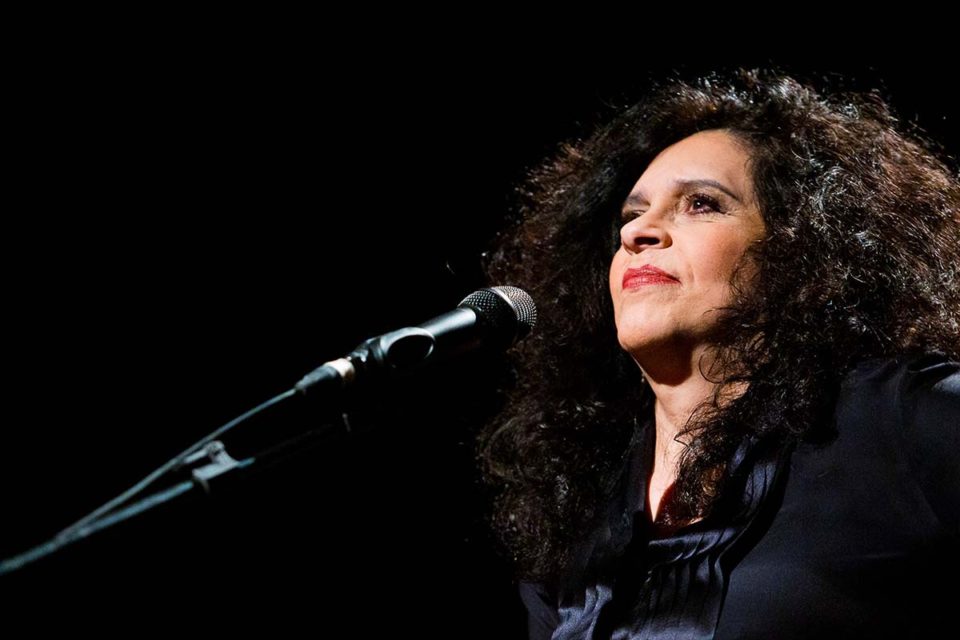 Cantora Gal Costa durante show. Ela aparece diante de microfone, olhando para a plateia - Metrópoles