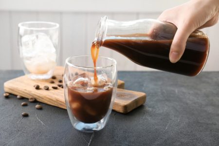 Na foto, um café é colocado em um copo transparente com gelo - Metrópoles