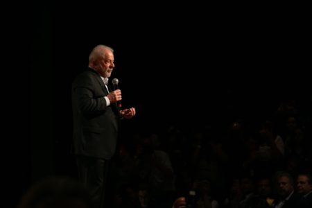 Imagem colorida mostra Luiz Inácio Lula da Silva, presidente eleito, em pé em um palco. Ele usa terno e segura um microfone - Metrópoles