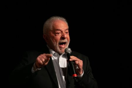 Imagem colorida mostra Luiz Inácio Lula da Silva, presidente eleito, em pé em um palco. Ele usa terno e segura um microfone - Metrópoles