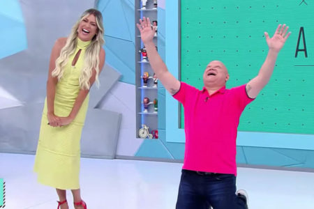 Renata Fan, de vestido amarela, ri da comemoração de Ronaldo Giovaneli, ajoelhado com as mãos para o céu, no Jogo Aberto - Metrópoles