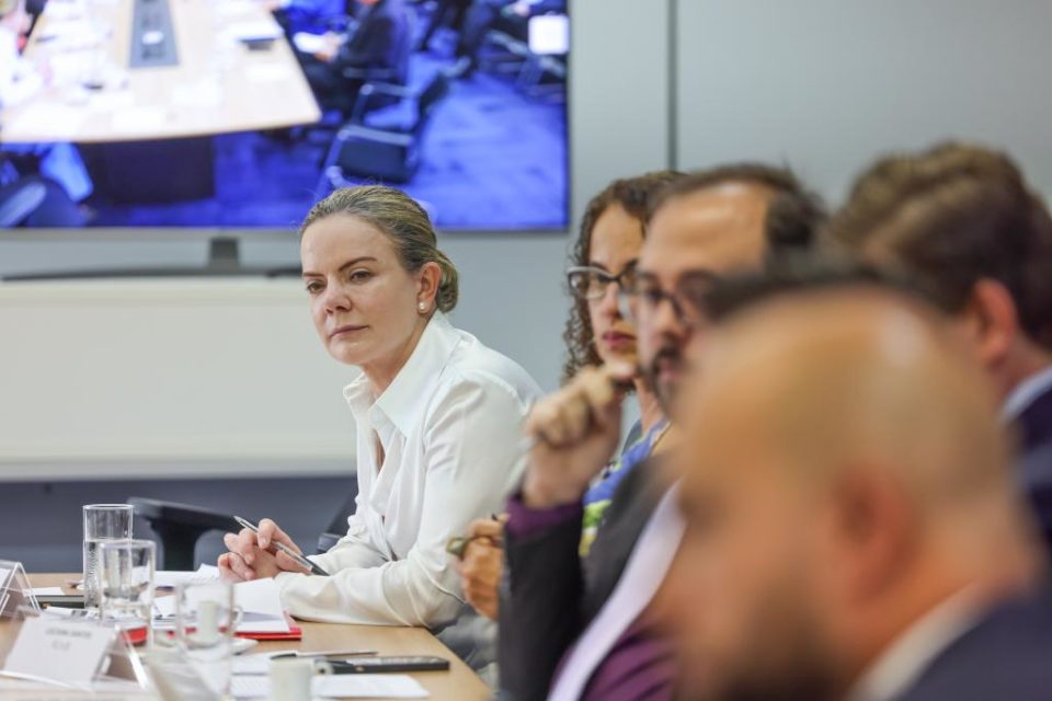 A presidente do PT, Gleisi Hoffmann, participando de reunião com lideranças de partidos aliados. Ela aparece debruçada sobre mesa, observando alguém falar - Metrópoles