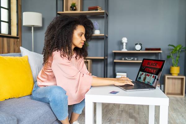 Mulher usando o laptop com um anúncio da Black Friday - Metrópoles