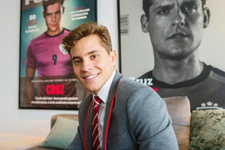 homem de uniforme escolar cinza posa sorrindo - Metrópoles