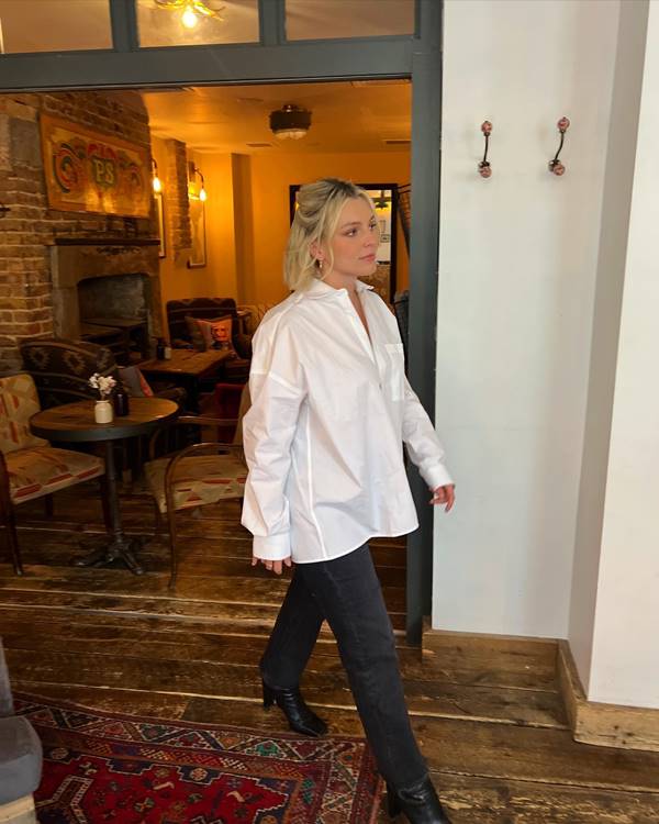 Estee Lalonde usando camisa branca, calça preta e bota preta - Metrópoles