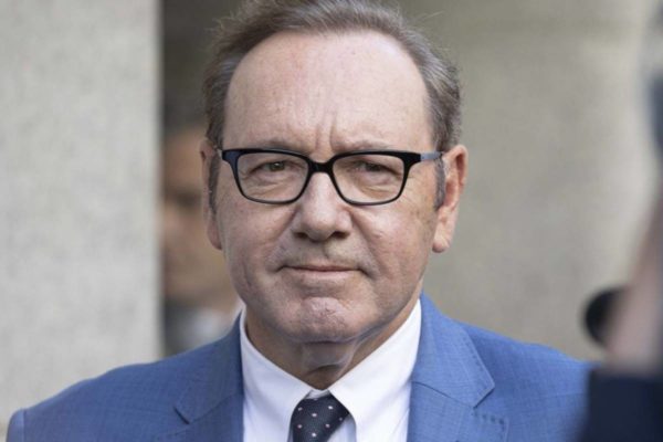 Kevin Spacey de camisa social clara, gravata preta cocm bolinhas e blazer azul claro e oculos de grau - metrópoles