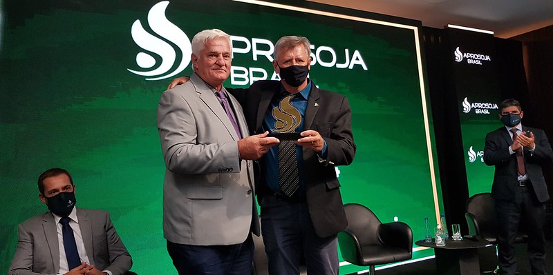 Ricardo Galvan e Bartolomeu Braz, dirigentes da Aprosoja, posam para foto segurando um troféu