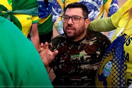 O jornalista e blogueiro bolsonarista Oswaldo Eustáquio conversa com militantes em frente ao QG do Exército trajado com roupas militares. Ele está em cadeira de rodas - Metrópoles