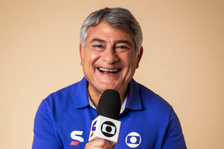 Cleber Machado, com o uniforme e o microfone da Globo, posa para foto - Metrópoles