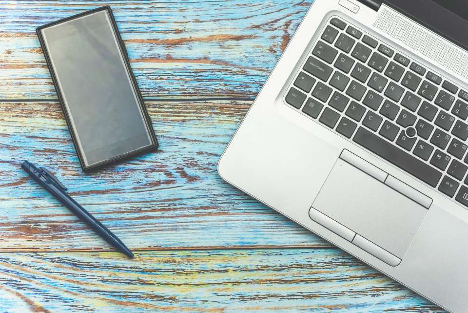Na foto, há um celular, uma caneta e um notebook em cima de uma mesa - Metrópoles