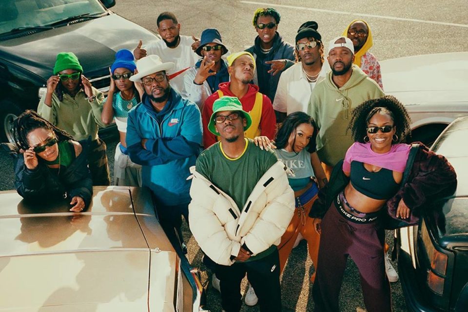 Campanha de divulgação da marca esportiva Nike. Na imagem, homens e mulheres jovens e negras aparecem fazendo poses ao lado de carros. Eles usam roupas descoladas, folgadas e estilosas da marca Nike. - Metrópoles
