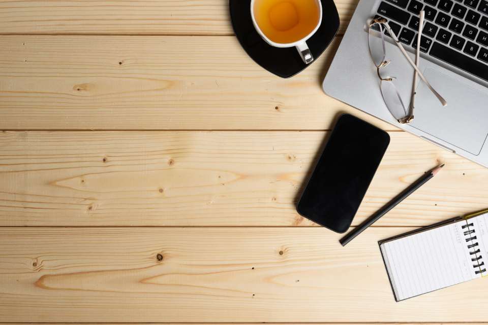 Na foto, há uma xícara de café, um celular, um notebook, um lápis e uma caderneta de anotações - Metrópoles