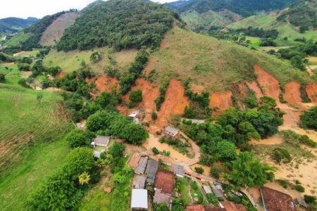 Imagem colorida: encosta com deslizamento sobre casas - Metrópoles