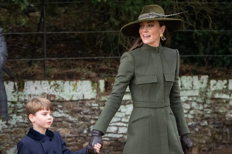 Foto colorida de menino branco e loiro de mãos dadas com mulher branca vestida com roupas na cor verde-militar - Metrópoles