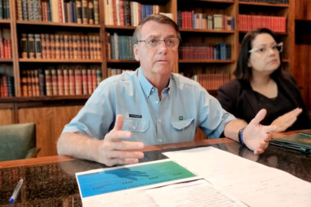 O presidente Bolsonaro, há dois dias de deixar o cargo, faz live no palácio do Alvorada antes de terminar mandato. Ele fala na biblioteca diante da mesa, ao lado de uma tradutora - Metrópoles