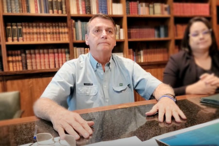 O presidente Bolsonaro, há dois dias de deixar o cargo, faz live no palácio do Alvorada antes de terminar mandato. Ele fala na biblioteca diante da mesa, chorando, ao lado de uma tradutora - Metrópoles