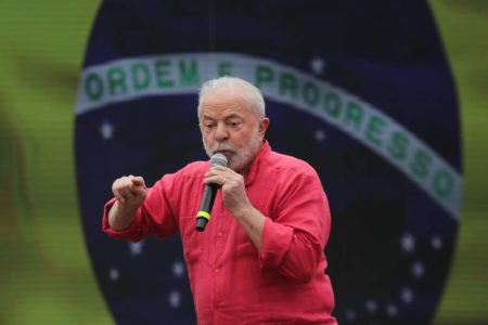 Foto colorida de lula discursando em frente a uma bandeira do Brasil