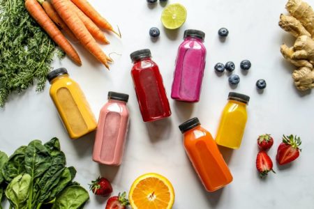 Alimentos e suxos detoz coloridos em um fundo branco - Metrópoles