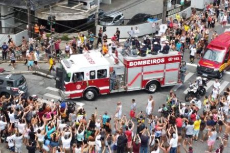 Em depedida ao jogador Pelé, cortejo fúnebre passa pela casa da mãe do atleta acompanhado por milhares de fãs e torcedores na cidade de Santos. Ao centro da imagem, o caminhão de bombeiros carrega o caixão - Metrópoles