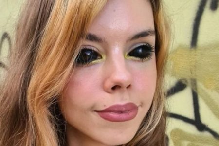 Jovem com olhos completamente pretos feito por tatuagem que a deixou cega. Ela é branca e tem cabelo ondulado - Metrópoles