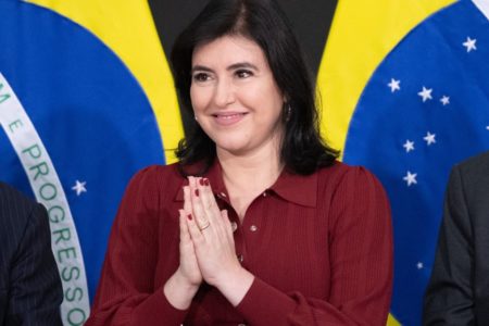 A cerimônia de posse da ministra do Planejamento e Orçamento, Simone Tebet, realizada no Salão Nobre do Palácio do Planalto. Na foto, a ministra aparece diante de bandeira do Brasil sorrindo e com as mãos juntas - Metrópoles