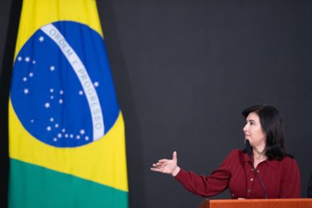 A cerimônia de posse da ministra do Planejamento e Orçamento, Simone Tebet, realizada no Salão Nobre do Palácio do Planalto. Na foto, a ministra aparece diante de bandeira do Brasil discursando em púlpito - Metrópoles