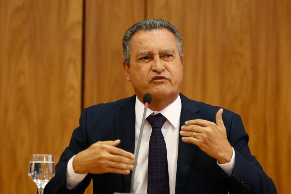 Ministro da Casa Civil, Rui Costa, concede entrevista coletiva sobre primeira reunião ministerial do governo Lula. Ele fala diante de microfone, sentado diante de mesa, e gesticula - Metrópoles