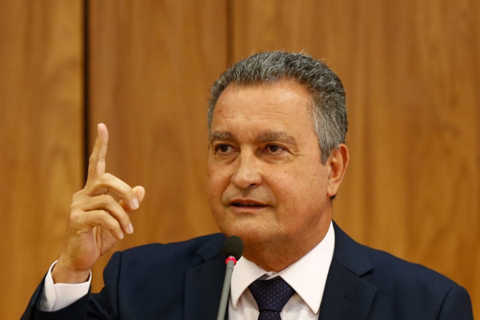 Ministro da Casa Civil, Rui Costa, concede entrevista coletiva sobre primeira reunião ministerial do governo Lula. Ele fala diante de microfone, sentado diante de mesa, e gesticula - Metrópoles