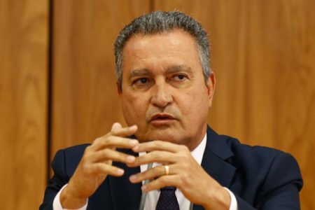 Ministro da Casa Civil, Rui Costa, concede entrevista coletiva sobre primeira reunião ministerial do governo Lula. Ele fala diante de microfone, sentado diante de mesa e gesticula - Metrópoles