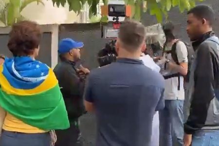 Jornalistas da Band são agredidos por militantes bolsonaristas e tem equipados quebrados em Belo Horizonte. Na imagem, eles são cercados por vários homens e uma mulher com bandeira do Brasil ataca uma das câmeras - Metrópoles