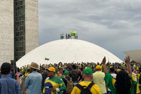 Imagem colorida de bolsonaristas em cima do Congresso Nacional