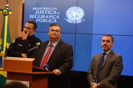 Ministro da Justiça, Flávio Dino, concede entrevista coletiva no Palácio da Justiça sobre a invasão e depredação dos prédios dos Três Poderes. Ele aparece ladeado por duas autoridades policiais - Metrópoles