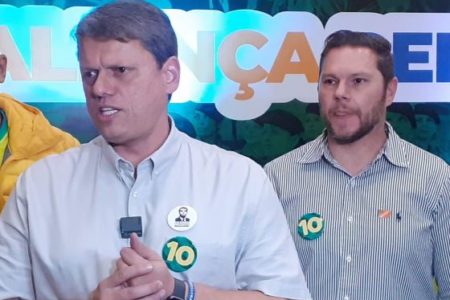 Imagem colorida mostra Tarcisio de Freitas e Danilo Campetti, homens brancos de camisa clara, em foto da cintura para cima na frente de um banner eleitoral - Metrópoles