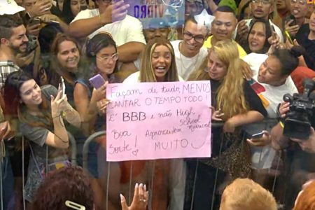 brunna gonçalves segura cartaz rosa em meio a multidão na frente da casa de vidro do bbb23 - metrópoles