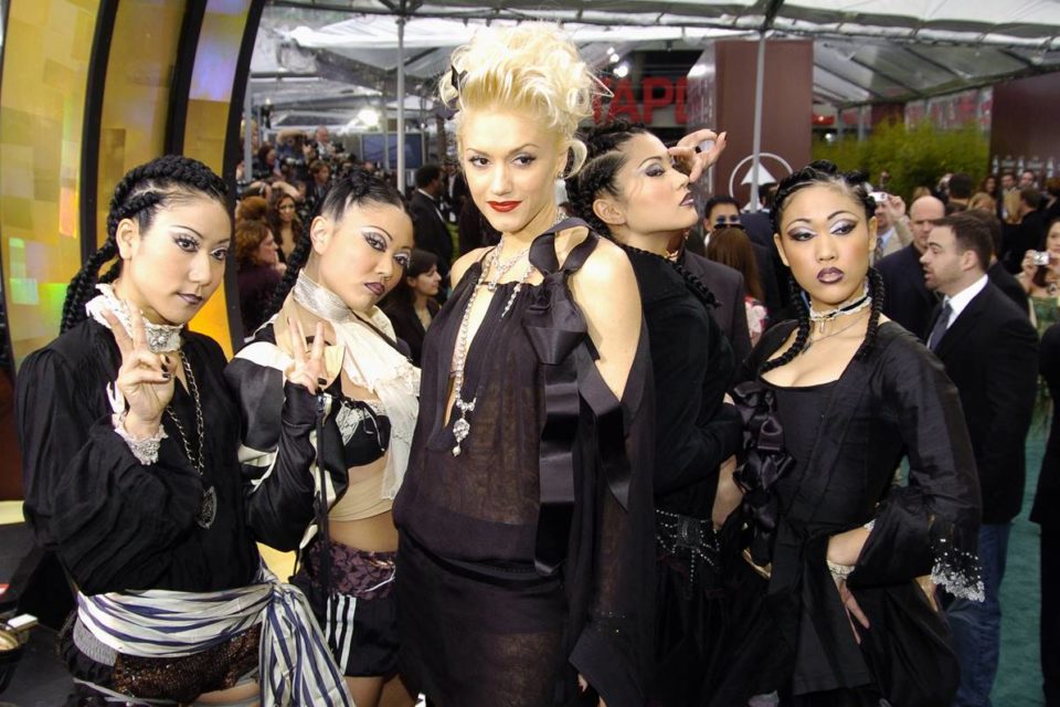 Na imagem com cor, Gwen Stefani ao lado das dançarinas Harajuku - Metrópoles