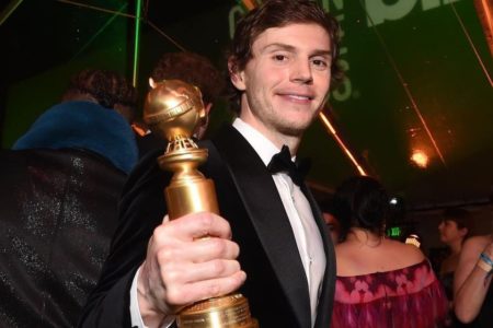 Evan Peters exibe o troféu do Globo de Ouro. Ele tem cabelo grande e loiro, veste um terno com gravada borboleta e sorri - Metrópoles