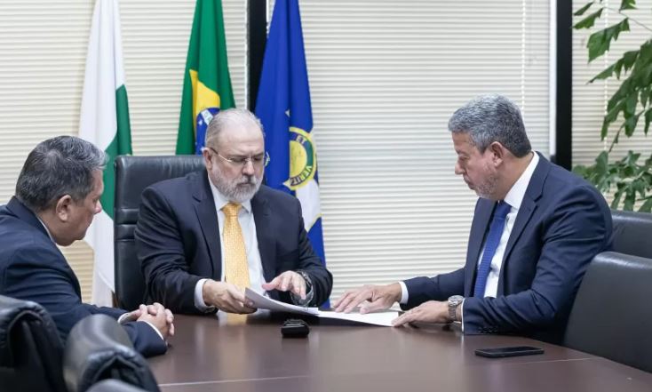 O procurador-geral da República conversa com o presidente da Câmara dos Deputados, Arthur Lira. Ambos estão sentados à mesa - Metrópoles