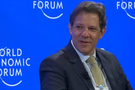 Fernando Haddad, ministro da Fazenda, no Fórum Econômico Mundial em Davos, Suíça. Ele olha para o lado, em frente a painel, durante fala - Metrópoles