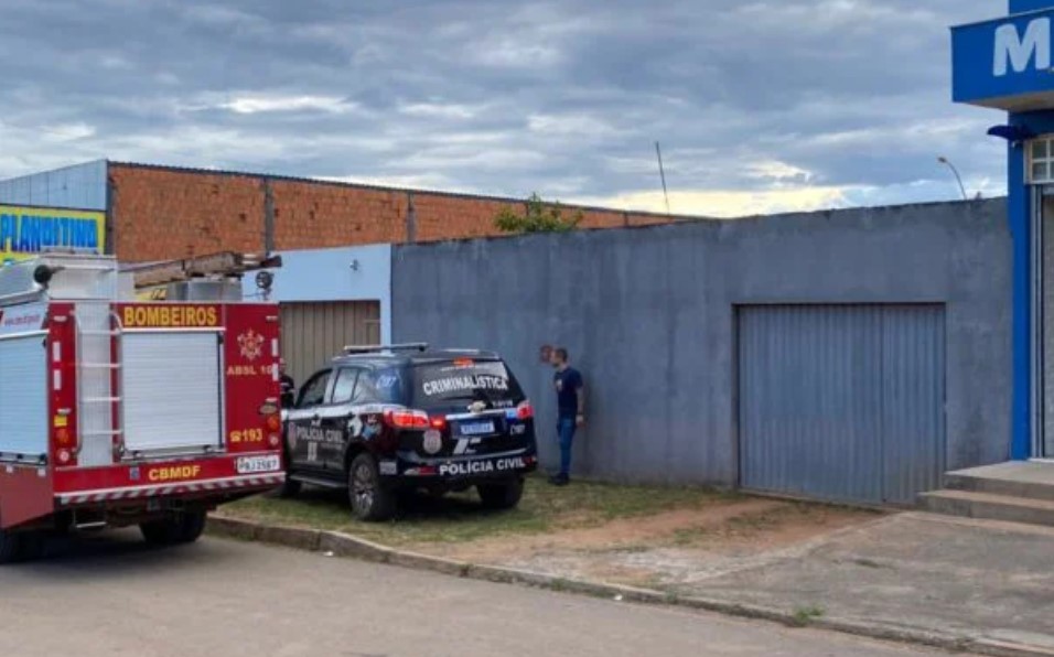 Fachada de casa em Planaltina usada como cativeiro de vítimas de família assassinada em chacina no Distrito Federal. Na porta, é possível ver um carro da PCDF, dos Bombeiros e um agente parado na frente - Metrópoles