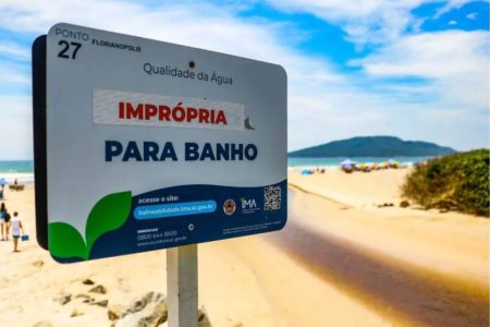 Foto colorida de uma placa em que informa que a praia está imprópria para banho - Metrópoles