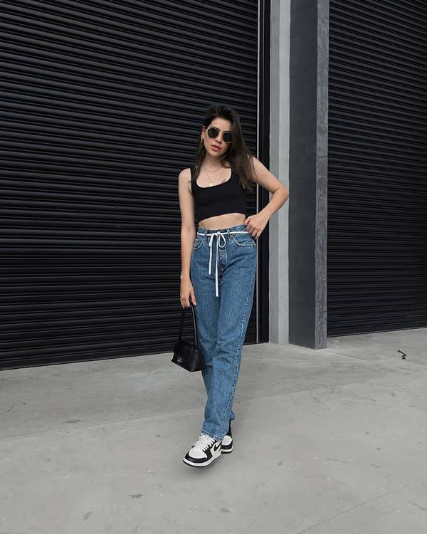 Mulher branca usa top preto e calça jeans - Metrópoles