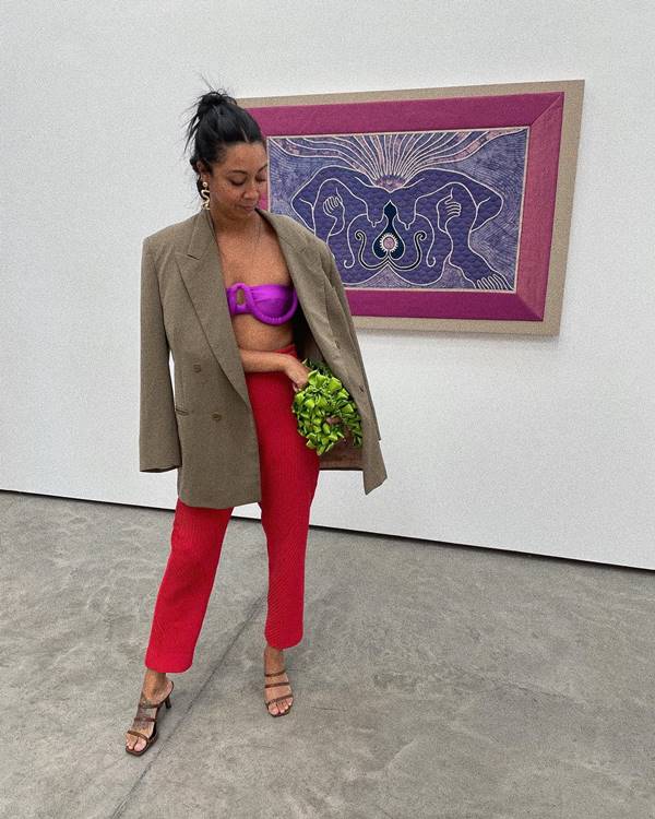 Mulher negra usa top roxo, calça vermelha, blazer e sandália de salto - Metrópoles