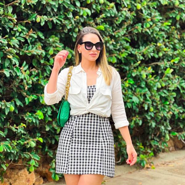 mulher branca com vestido estampado de camisa branca por cima - Metrópoles