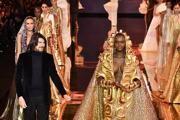 Mulher negra vestida com capa dourada em desfile de moda na passarela - Metrópoles