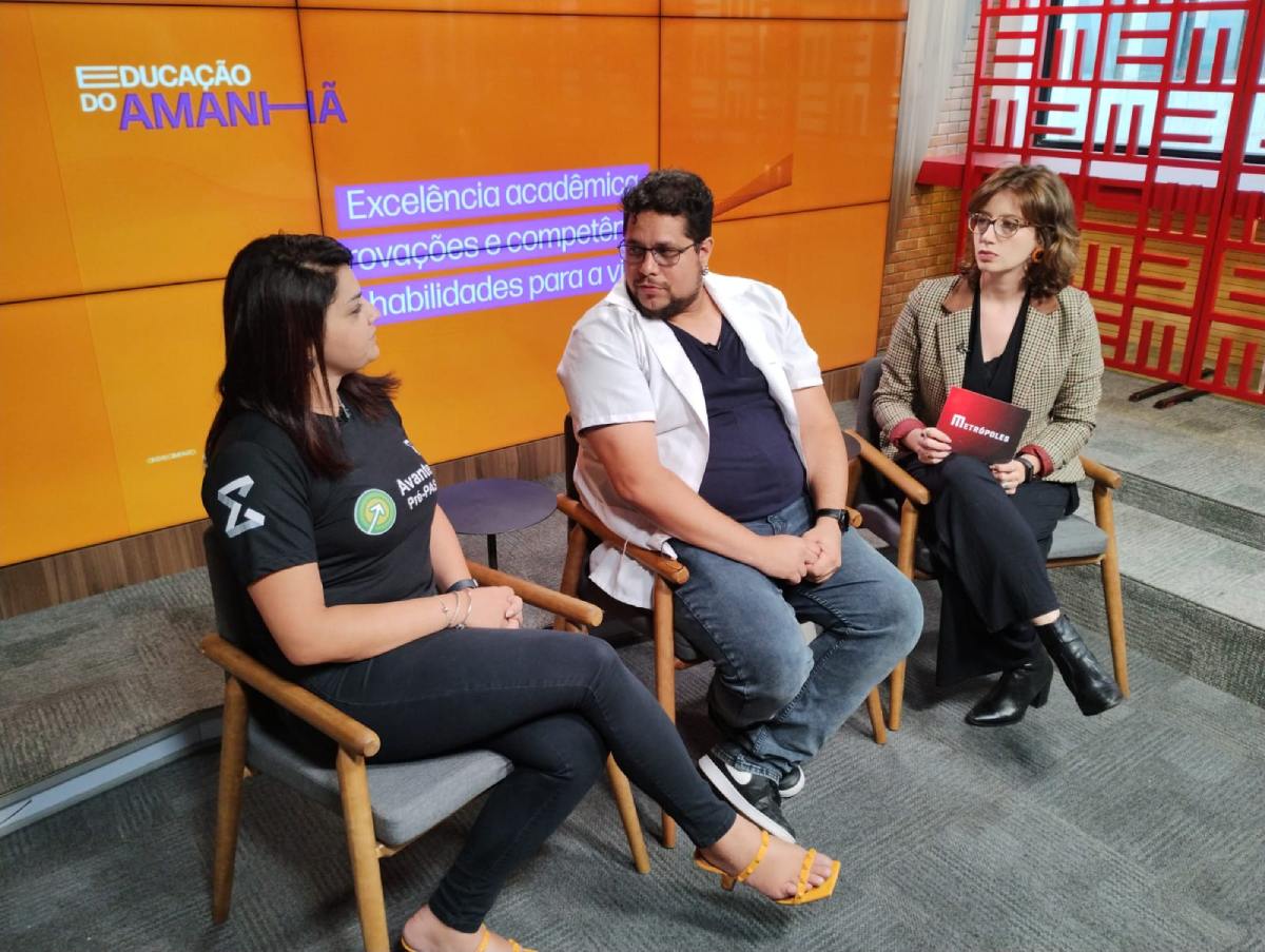 Professores Juliana e Flávio do colégio Sigma, de Brasília, dão entrevista para a jornalista do Metrópoles, Natália André solbre o tema "Excelência acadêmica: provações e competência como habilidades para a vida". Eles aparecem sentados em estúdio - Metrópoles
