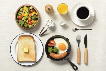 Mesa de café da manhã farta com ovos, pães e líquidos