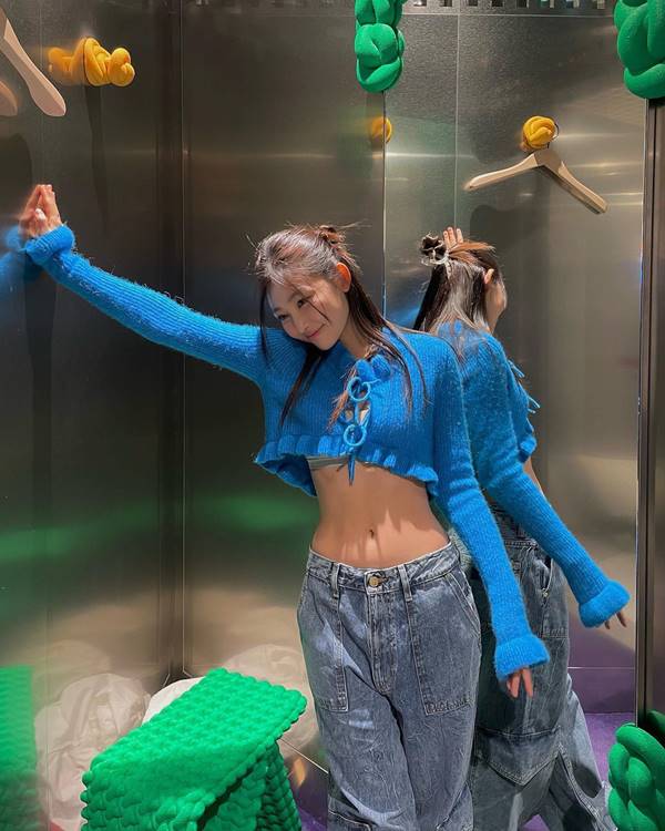 Modelo asiática pose em elevador usando casaco azul e calça de cintura baixa - Metrópoles
